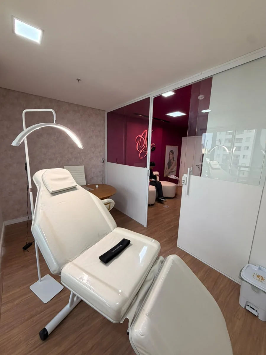 Sala de atendimento com poltrona branca e luminária, vista para a recepção