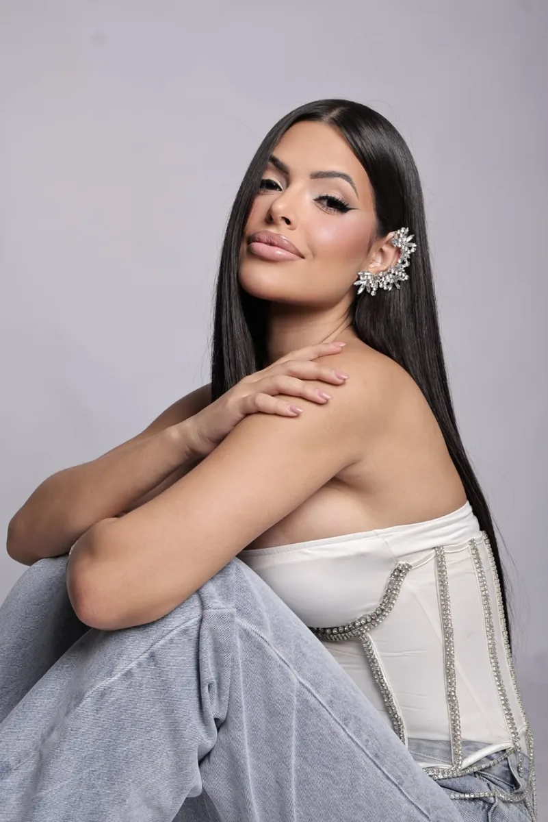 Dra. Mari Duds sentada, de perfil, olhando para a câmera